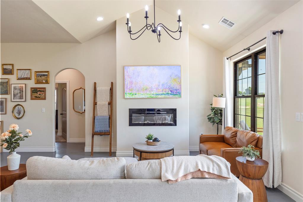 Tessa Hood Realtor – Living room with electric fireplace, vaulted ceiling, and chandelier at 1074 Fawn Meadow Dr, Blanchard Oklahoma
