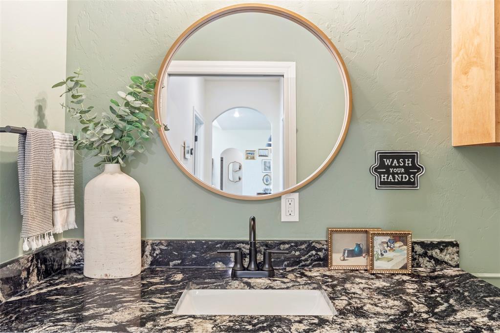 Tessa Hood Realtor – Powder bath with granite countertop and round gold-frame mirror at 1074 Fawn Meadow Dr, Blanchard Oklahoma
