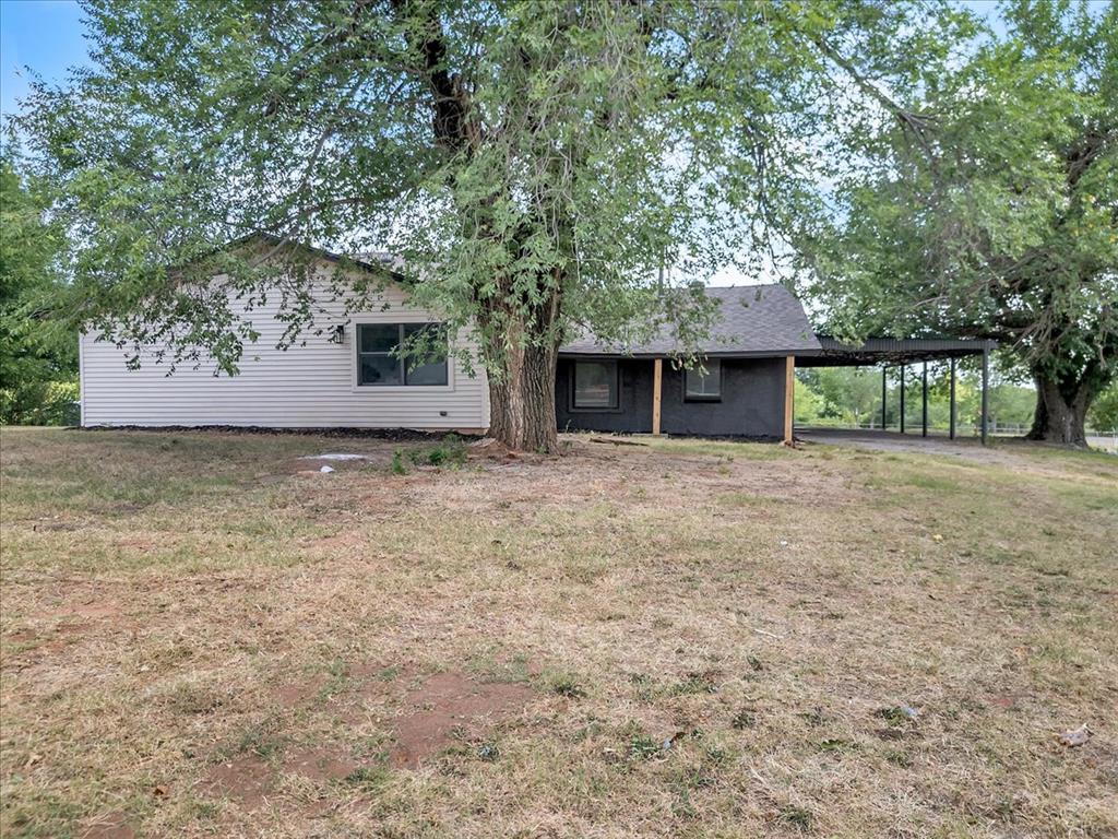 Tessa Hood Realtor – Exterior front of remodeled home with mature trees and covered carport at 7400 Lakewood Dr, Mustang Oklahoma