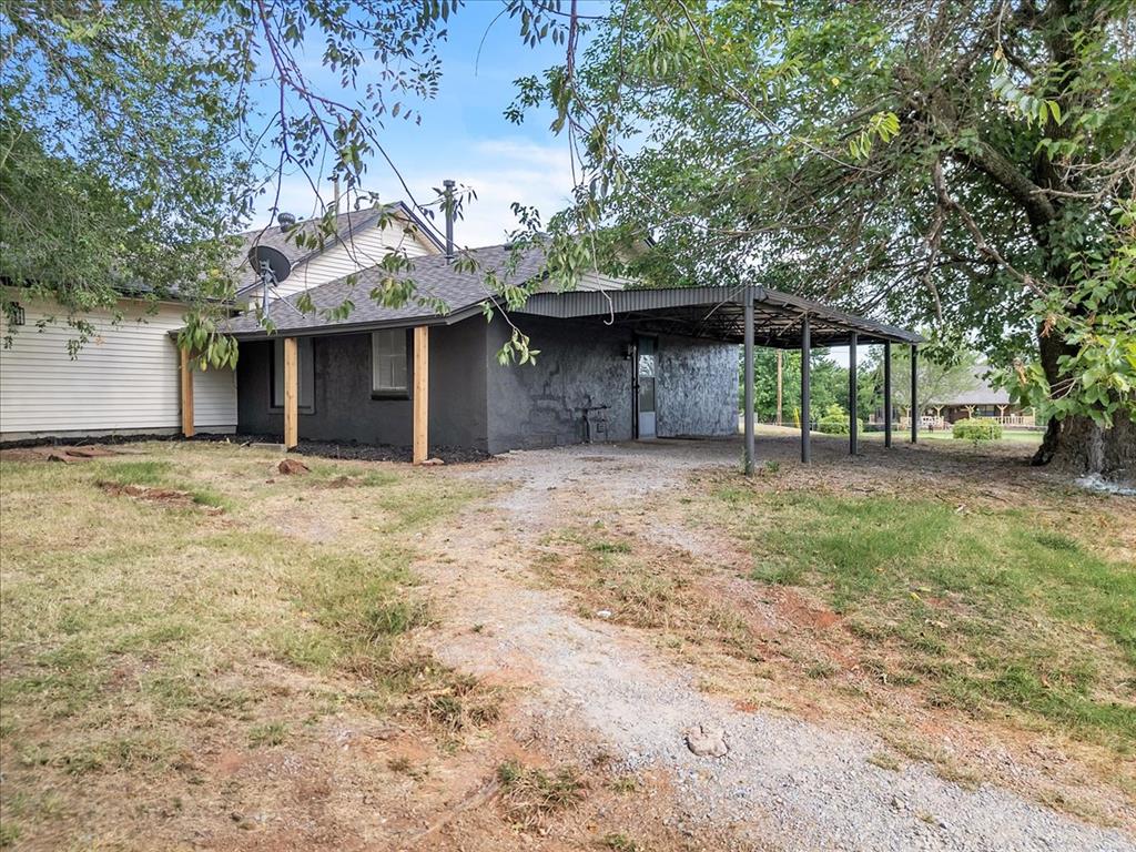 Tessa Hood Realtor – Side exterior showing covered carport and gravel driveway at 7400 Lakewood Dr, Mustang Oklahoma